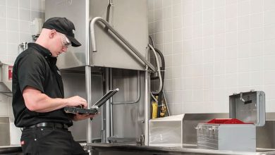 یک تعمیر کار درحال تعمیر ماشین ظرفشویی صنعتی